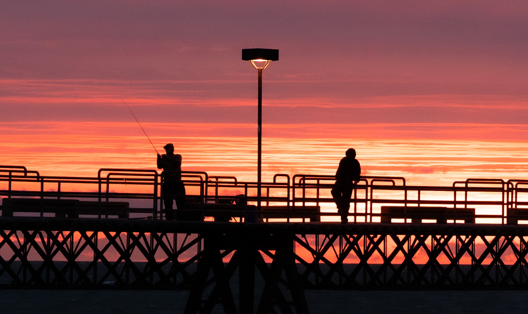 People silhouetted on a pier at sunset